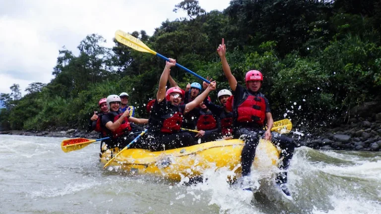 A group of tourists paddling in perfect synchronization during their rafting in baños ecuador tour